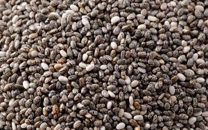 A close-up view of chia seeds, showing a mixture of small black, white, and grey seeds, highlighting the appearance of the superfood rich in nutrients.